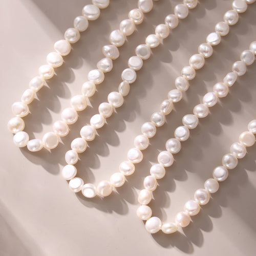 Multiple strands of irregular white baroque pearls on pale surface