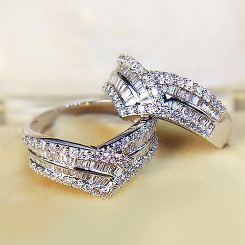 Two white gold V baguette crystal rings stacked on cream surface