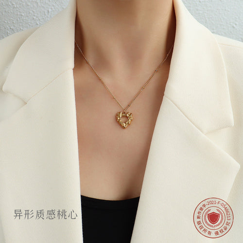 Gold textured open heart pendant necklace worn with blazer
