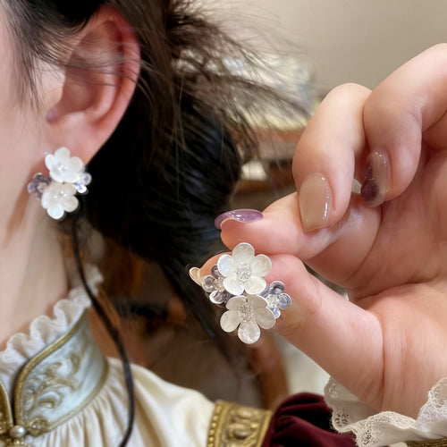 Product display of blue enamel flower stud earrings with clear crystal centers