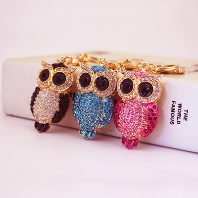 Three owl keychains in black, blue and pink displayed together.