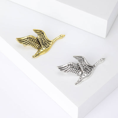 Front view of the flying bird brooch showing a textured flying bird silhouette in an antiqued metal finish