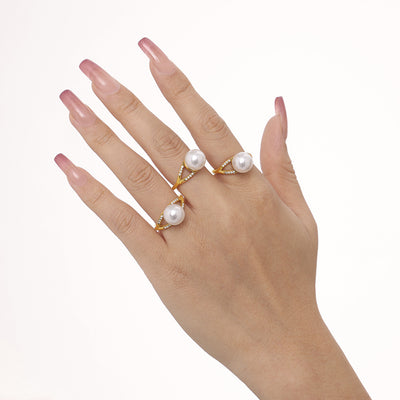 Hand wearing three gold imitation pearl open rings on fingers