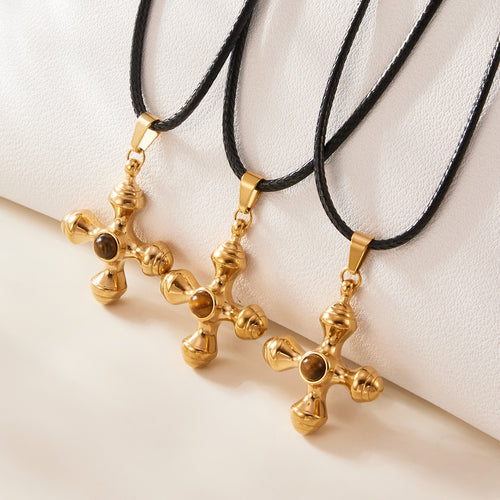 Three gold tiger eye cross pendants on black cords close-up