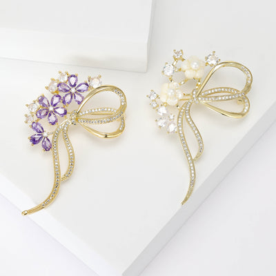 Two colorways of long-tail crystal bow brooch with a compact floral spray shown side by side.