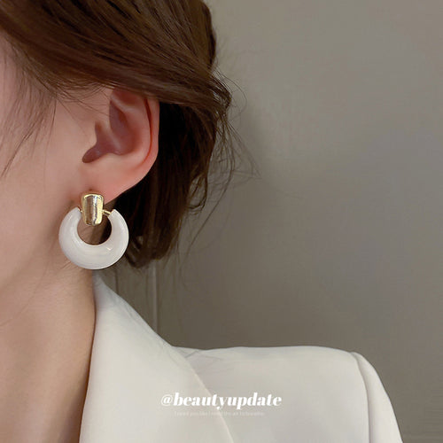 White Layered Ring Gold Stud Earrings Polished Metal Jewelry modeled at the ear