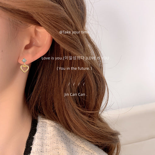 Model wearing gold CZ open heart dangle stud earring