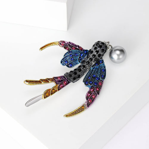 Rainbow crystal swallow brooch angled on white geometric platform