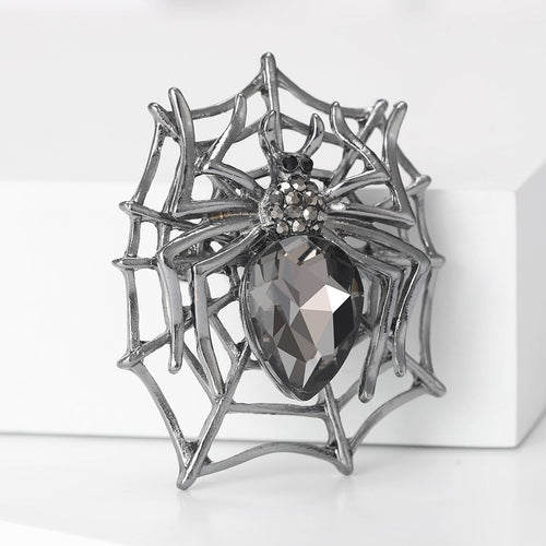 A sculpted web holding a dark metal spider with faceted abdomen shown in a styled display.