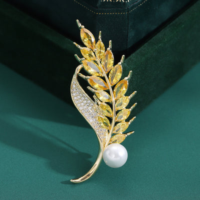 Front view of yellow crystal wheat brooch with clear leaf and pearl-like accent against a white background.