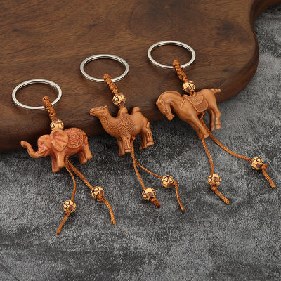 Three brown animal keychains shaped as an elephant, camel, and horse on a gray surface.