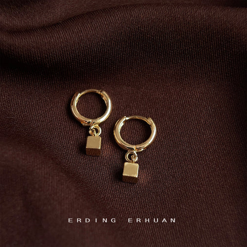 Gold-tone cube drop huggie pair on brown cloth