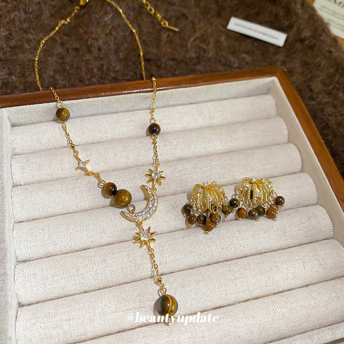 Gold tiger eye moon star necklace and firework studs on jewelry tray