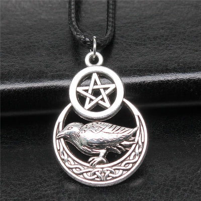 Close-up of raven pentagram cord necklace showing a raven, crescent, and pentagram pendant on a black cord