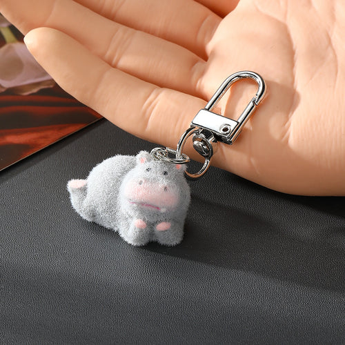 Gray hippo keychain with both pink hands on head held in palm