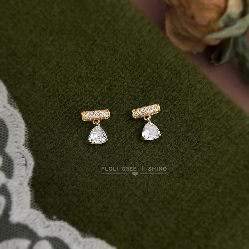 Gold bar studs with clear teardrop drops on green fabric