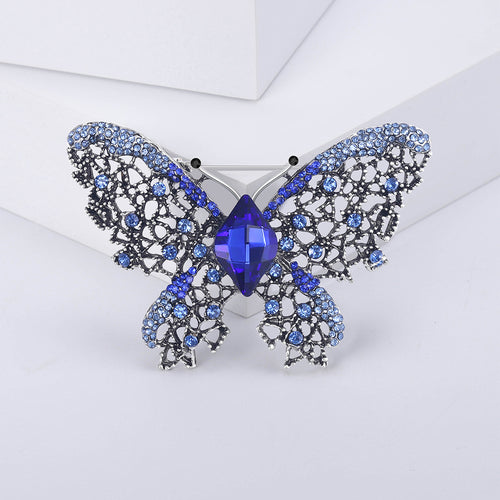 Blue rhinestone butterfly brooch close-up on white geometric blocks
