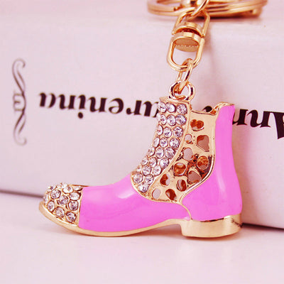 Close-up of a pink boot keychain decorated with clear rhinestones and gold-tone trim.