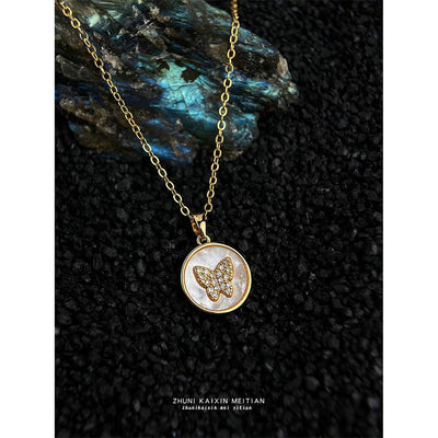 Gold shell butterfly pendant necklace on black grit with stone