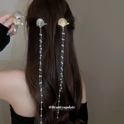 Gold and silver shell hair clips with pearl chains worn in long hair