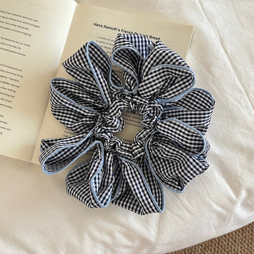 Blue gingham petal scrunchie with light blue edge on open book