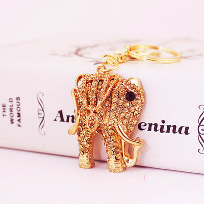 Close-up of a rhinestone elephant keychain resting against a book.