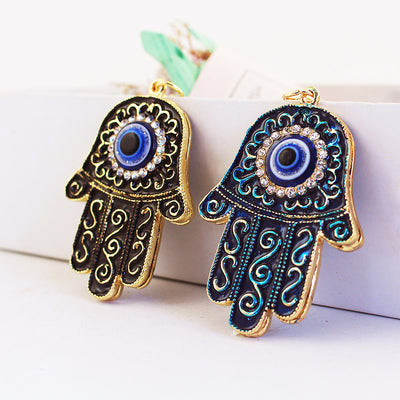 Two blue and black Hamsa hand charms with evil eye centers and clear rhinestone borders.