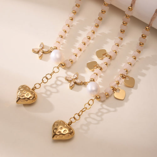Close-up of puffed gold heart pendant pearl and zircon butterfly charms