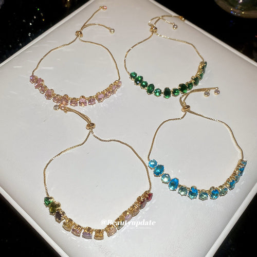 Four gold crystal slider bracelets laid open on white tray