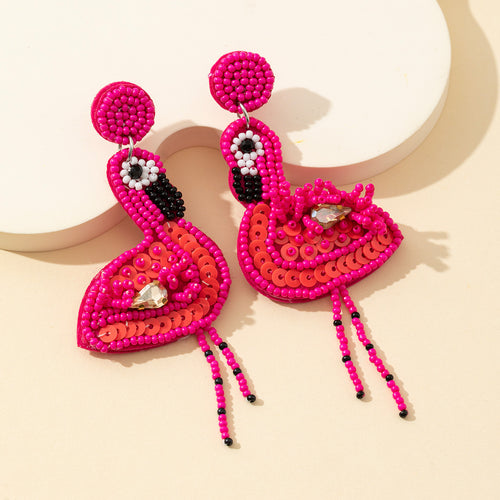 Pair of rose red beaded sequin flamingo earrings with fringe legs on a cream background