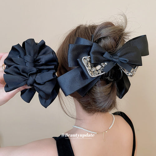 Woman wearing black rhinestone bow claw holding ruffle claw