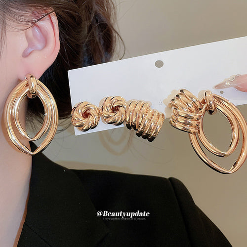 Gold double hoop earring worn with matching gold set on card held nearby