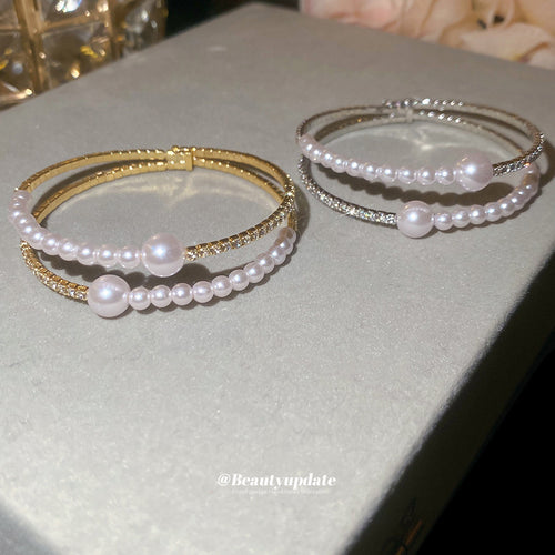 Gold and silver double row pearl open cuffs on gray surface