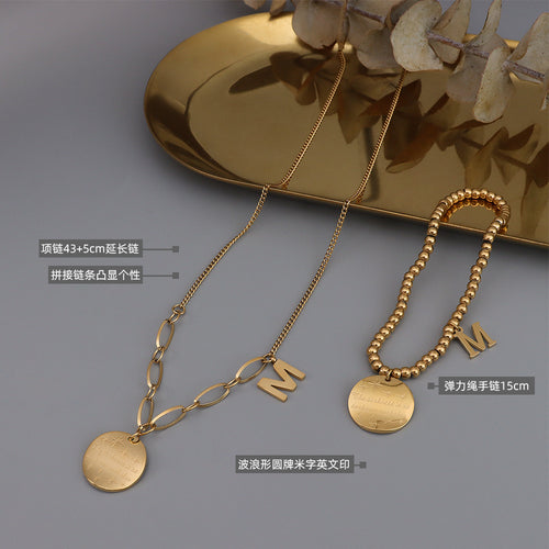Gold wave disc necklace and beaded bracelet flat lay with size labels