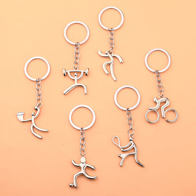 Six silver-tone sports figure keychains arranged on a peach background.