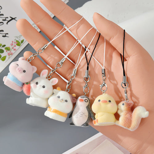 Hand holding six flocked animal phone charms pig bunny cow penguin duck squirrel