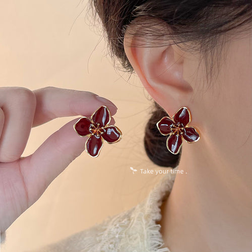 Ankara red enamel flower stud worn on ear with matching earring held