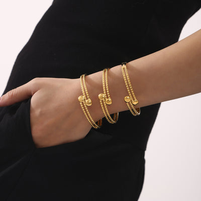 Three gold double layer open ball tip bangles stacked on model arm