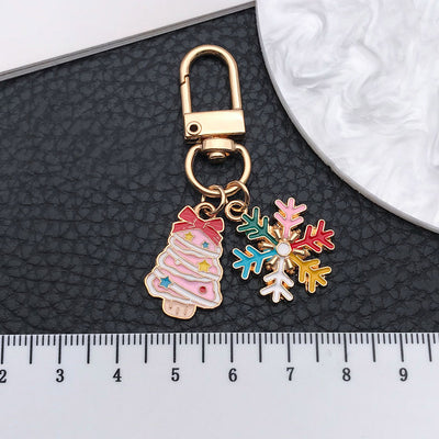 Grouped pink Christmas tree and multicolor snowflake keychain arranged together on a styled display surface