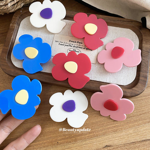 Assorted acrylic flower clips in four colors on wood tray