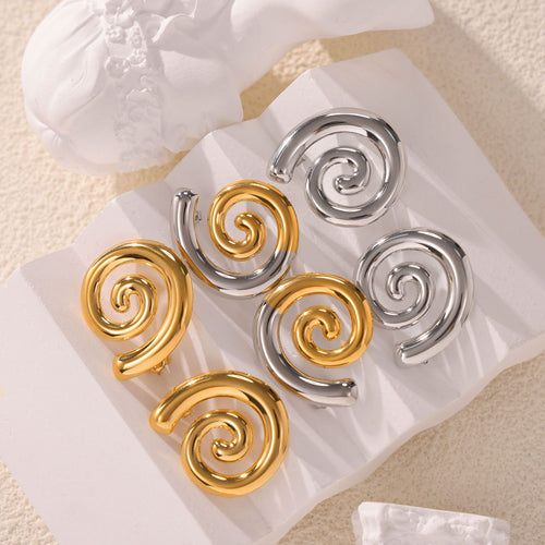 Gold steel and two-tone spiral studs on white stone display