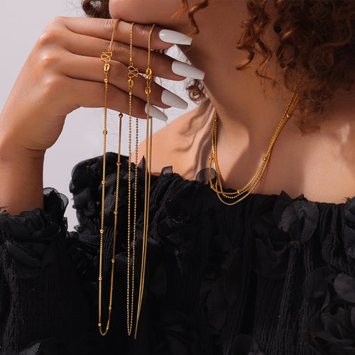 Model holding multi gold chain strands wearing layered gold necklaces
