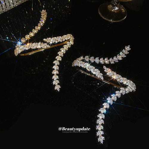 Gold and silver leaf crystal open cuffs displayed on black reflective surface