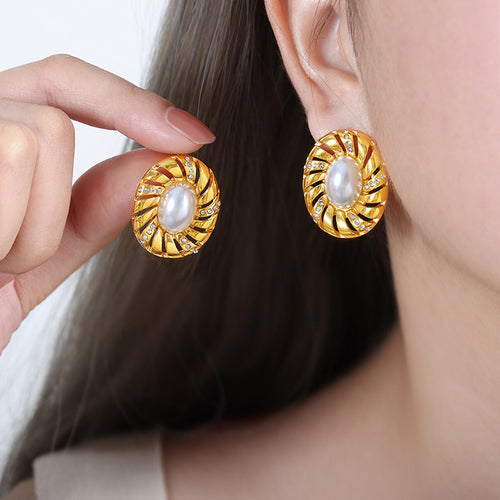 Model holding and wearing gold oval swirl stud with pearl center and crystals