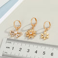 Gold Tone Huggie Earrings with Crystal Daisy and Bow Charm Drops view 2