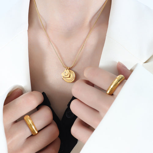 Gold dual moon and R seal pendant necklace worn with white blazer