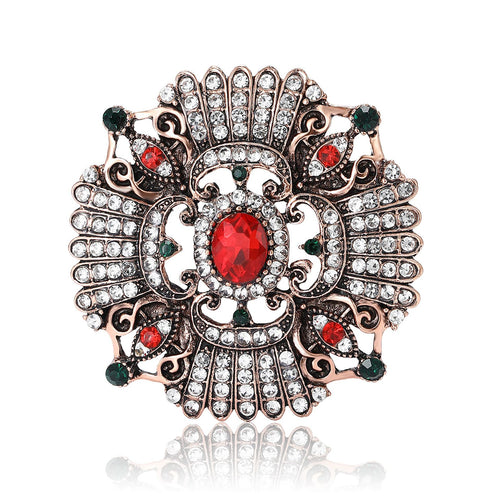 Front view of ornate round medallion centered by a red oval stone