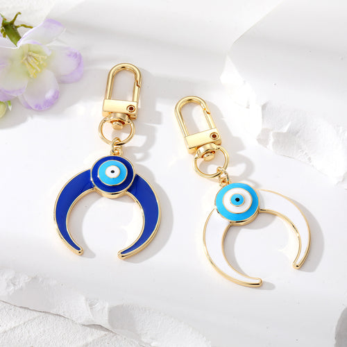 Blue and white enamel crescent moon evil eye keychains side by side