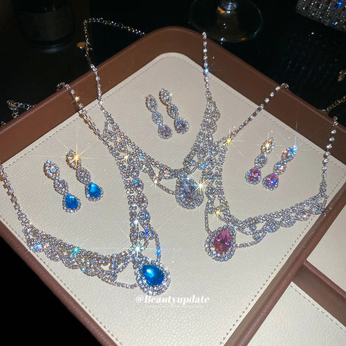 Three silver scalloped teardrop necklace sets on beige tray