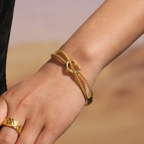 Close-up of single gold beaded heart clasp bangle on wrist